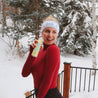 Woman in red sweater and black leggings holding a product in a snowy outdoor setting