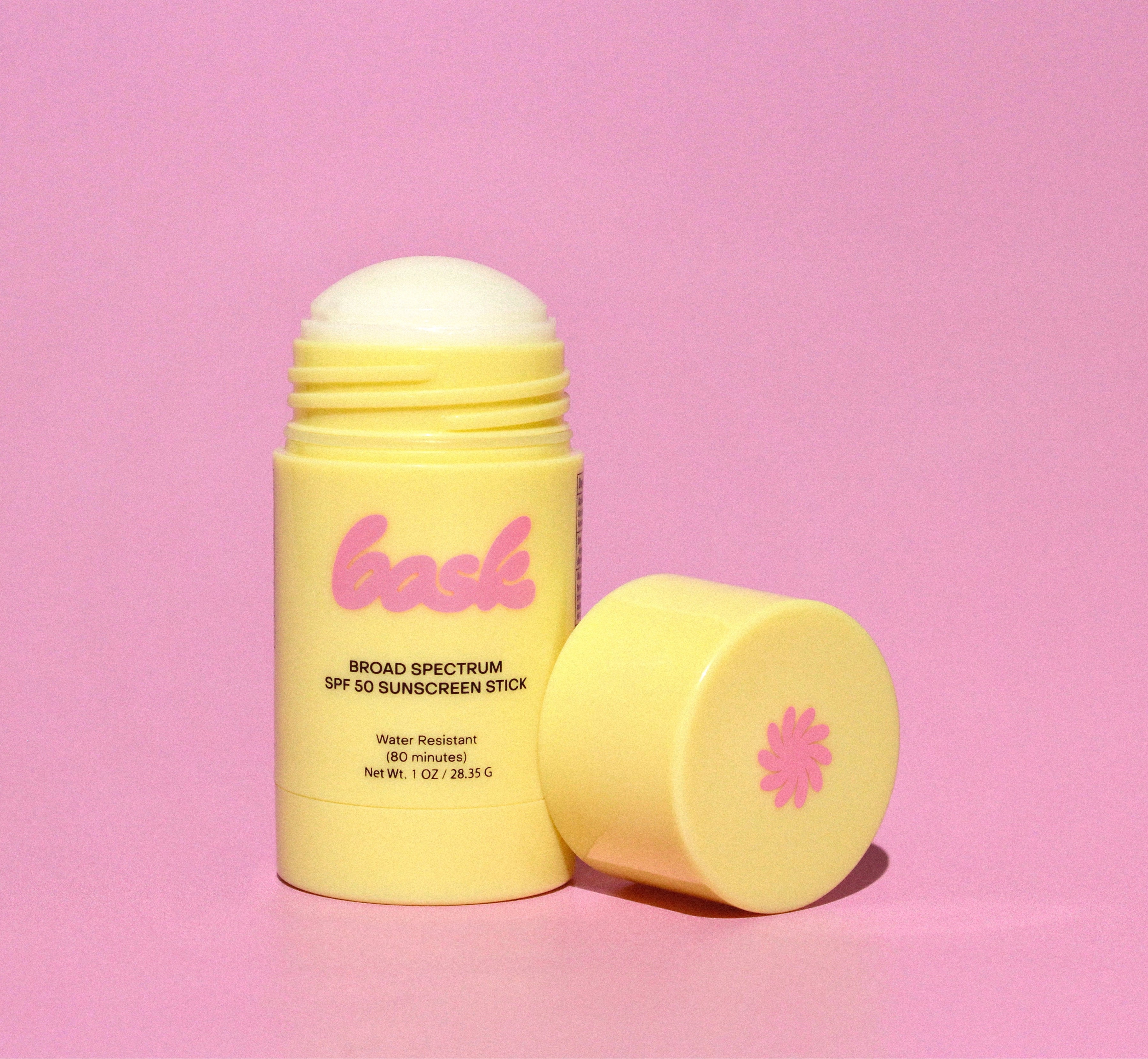 Yellow sunscreen stick with pink logo on a pink background