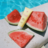 Bottle of Vacation Sunscreen Sitting Among Watermelon Next To A Pool