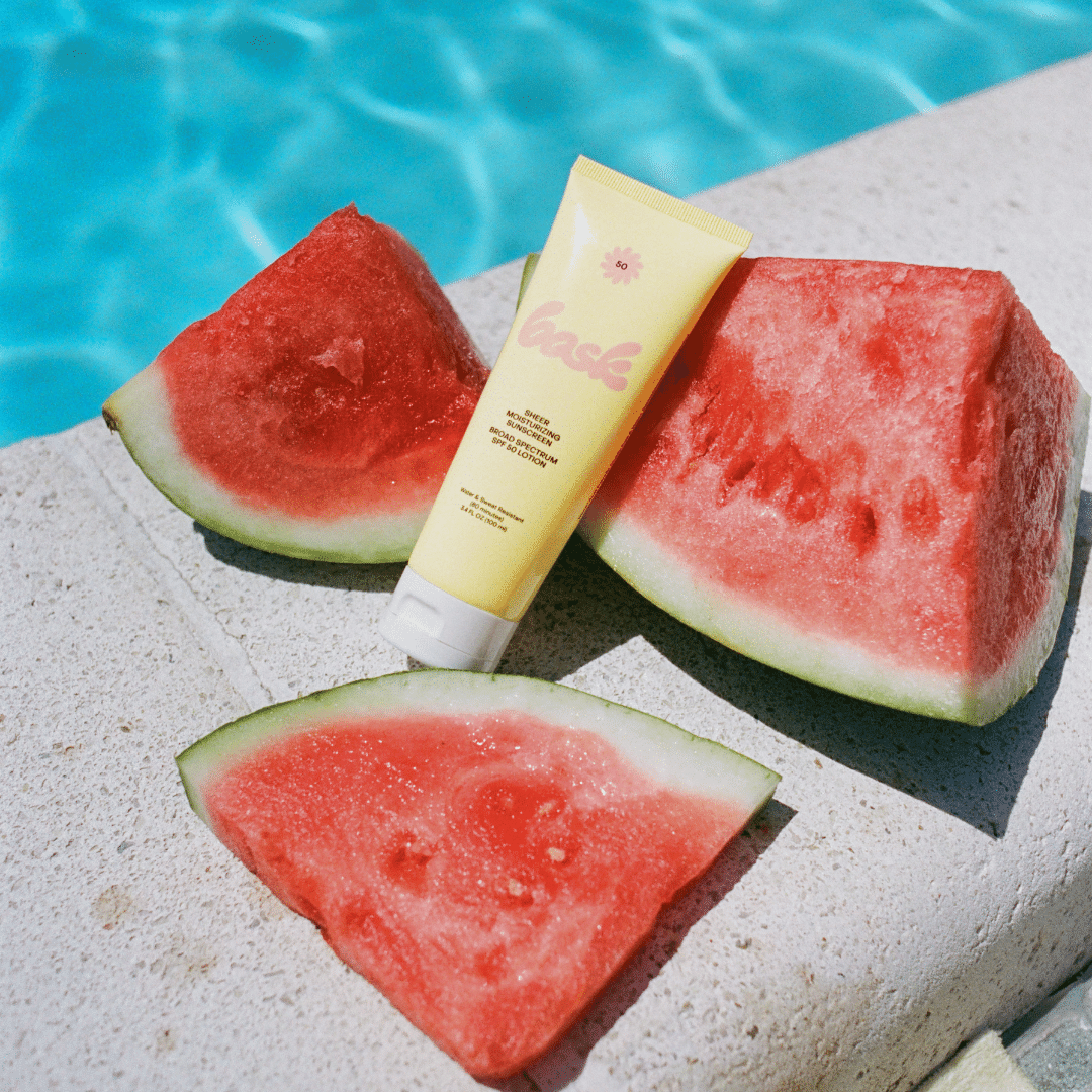 Bottle of Vacation Sunscreen Sitting Among Watermelon Next To A Pool